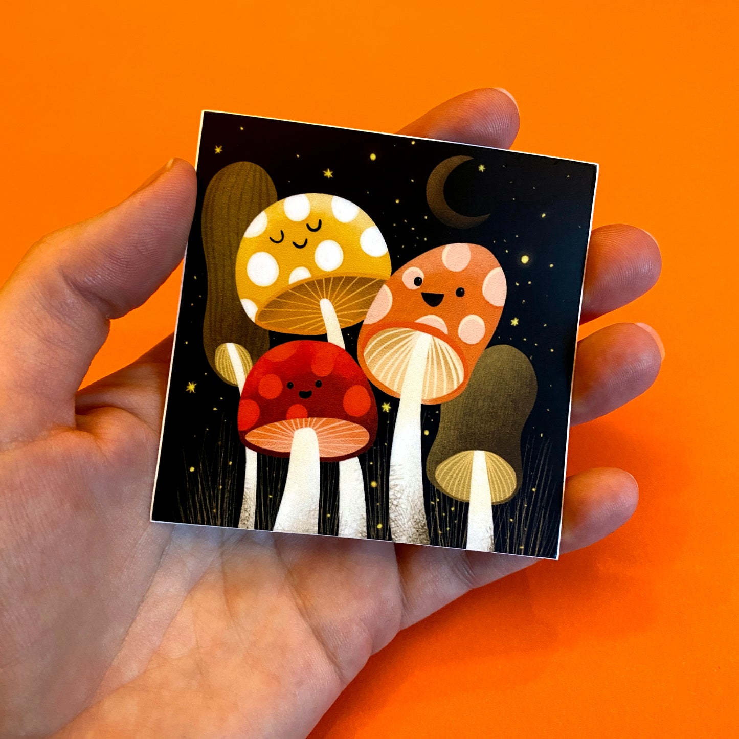 Vinyl sticker featuring an adorable group of happy mushrooms! Original art by Anna Fox Sticker printed with a matte finish on premium vinyl with a strong adhesive. Waterproof, Dishwasher safe and scratchproof sticker that is made to last! 3 inches x 3 inches square sticker. Wrapped in a protective plastic sleeve that is made of plant- based polylactic acid (PLA) and is certified compostable