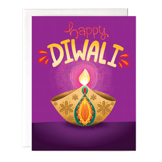 A purple Diwali card that has an ornate diya illustration and says “happy Diwali” at the top. Size a2 greeting card, blank inside with white envelope.