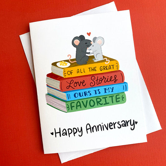 adorable anniversary greeting card with two cute mice sitting on top of a stack of books. The books read "of all the great love stories ours is my favorite". At the bottom it says "Happy Anniversary".