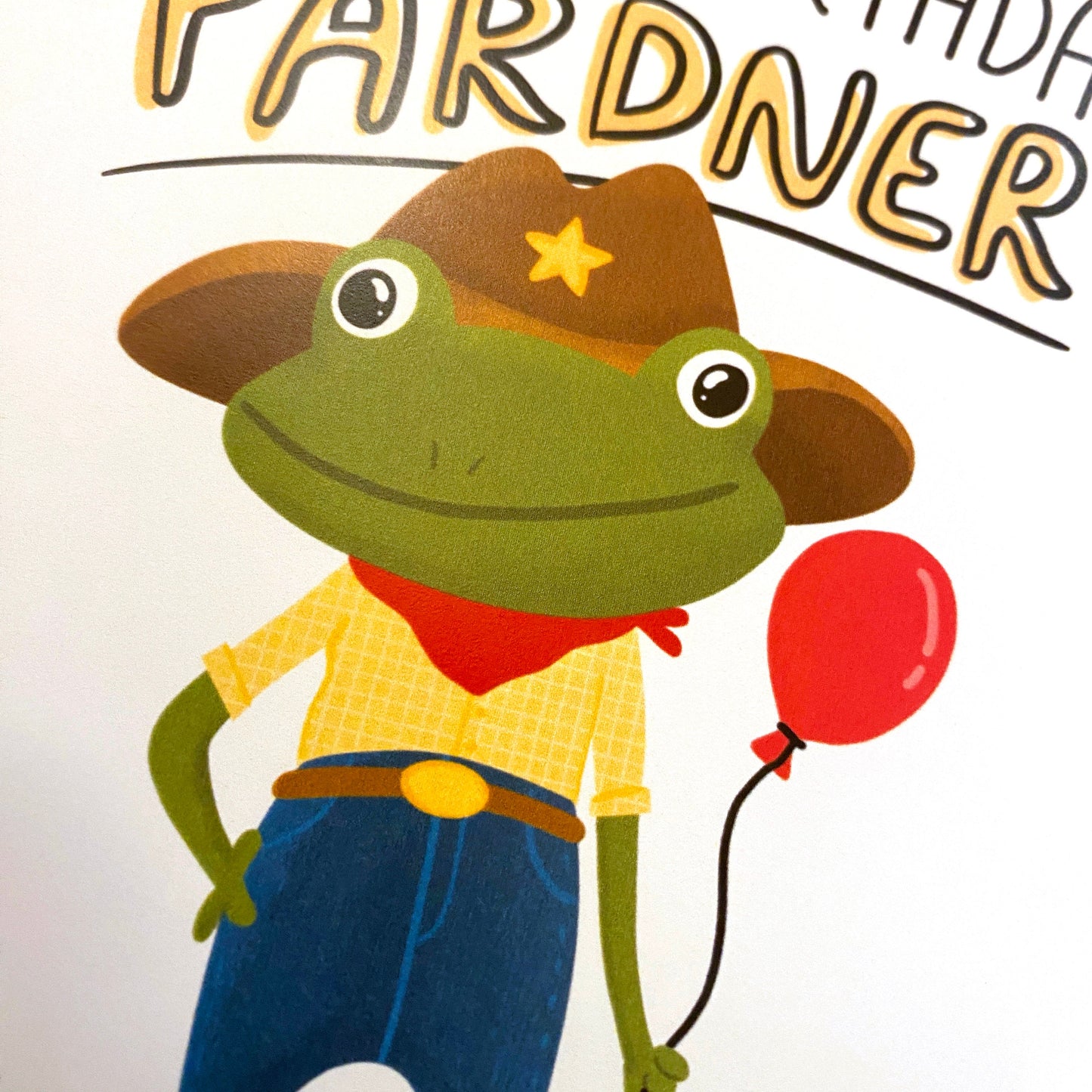This cute cowboy frog is a funny way to say happy birthday PARDNER. Yeehaw! Size A2 greeting card (4.25&quot; x 5.5&quot;) with envelope- Blank Inside. All cards are designed and Illustrated by Anna Fox and are printed  in Denver, CO.