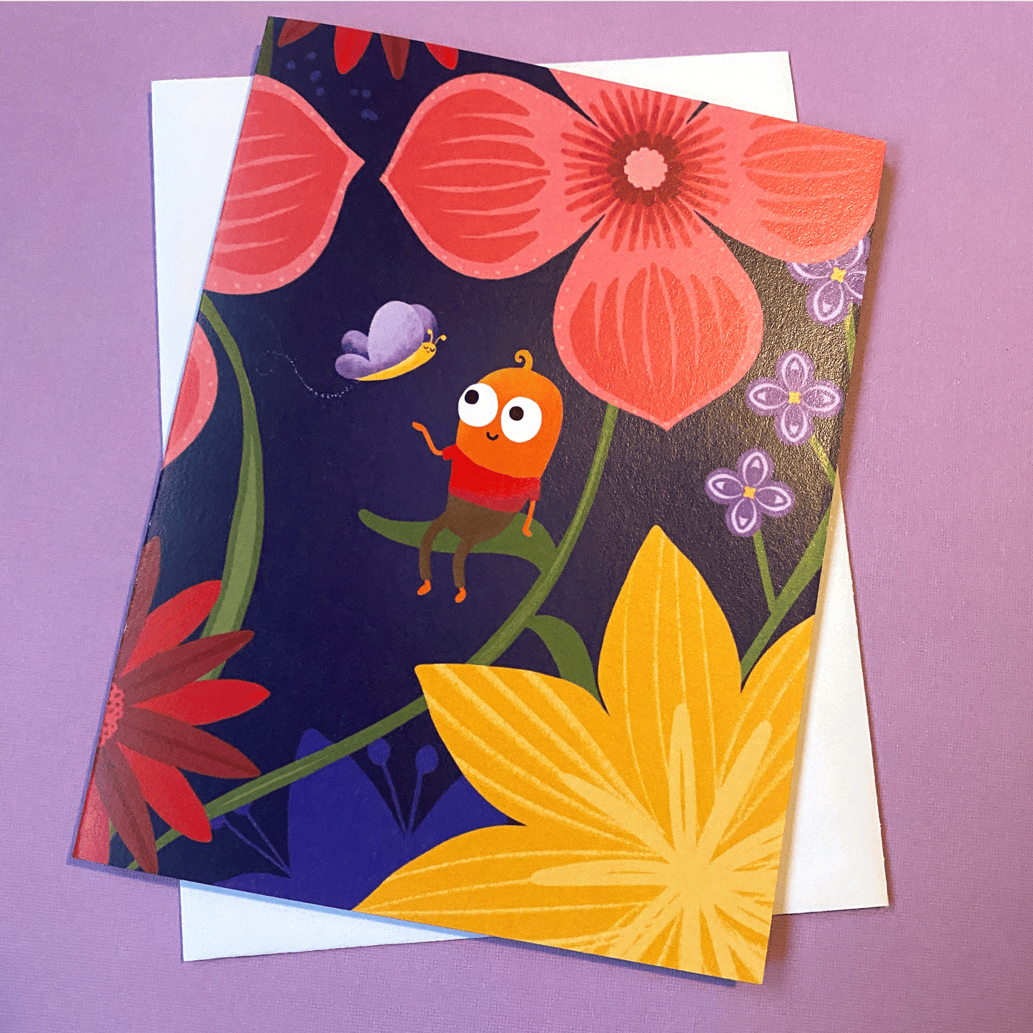 This adorable card features a cute little guy sitting on a leaf in a garden with his hand out for a butterfly. 