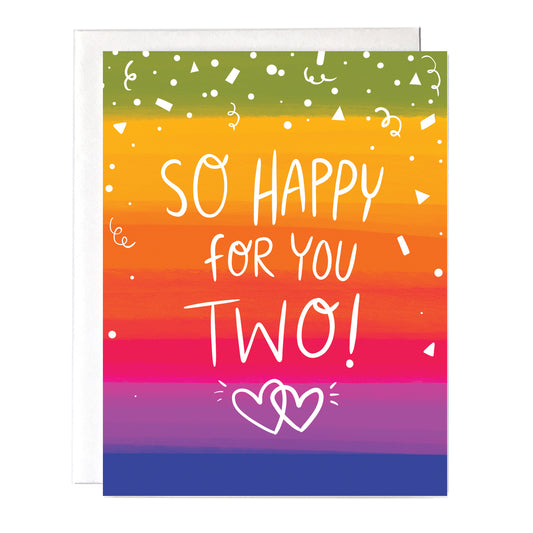 A greeting card with a colorful rainbow background with the words "So happy for you two" on the front. black inside size a2 greeting card with white envelope.